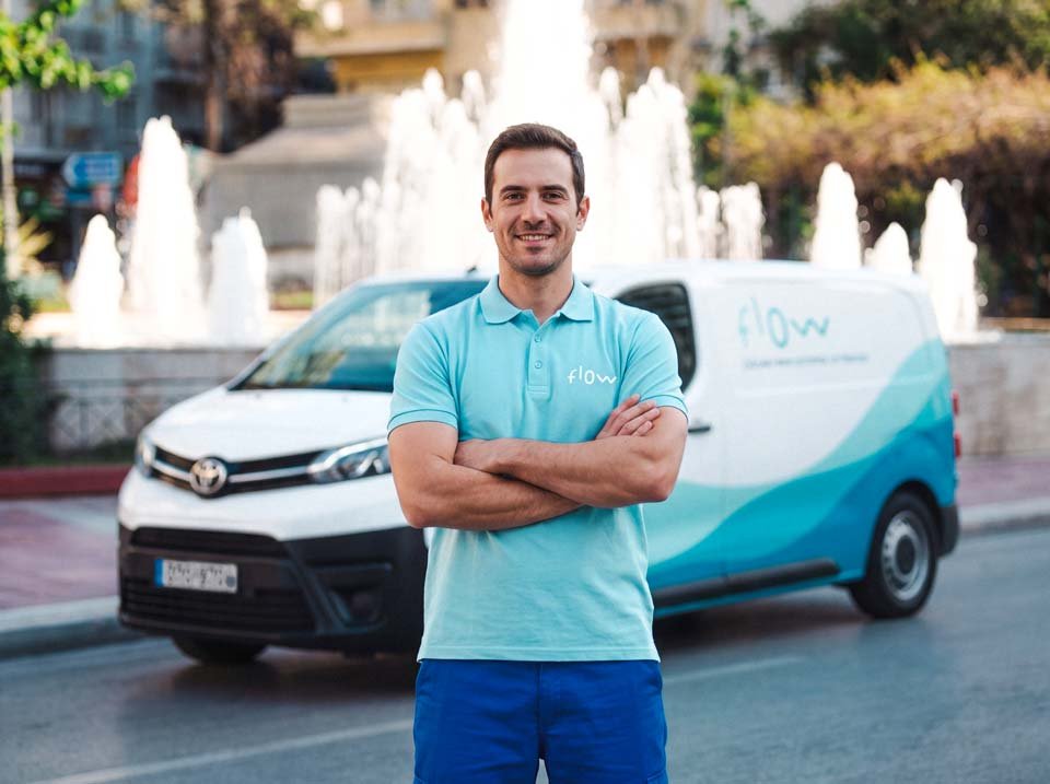 Τεχνικός της Flow με στολή, μπροστά από το van και ένα σιντριβάνι